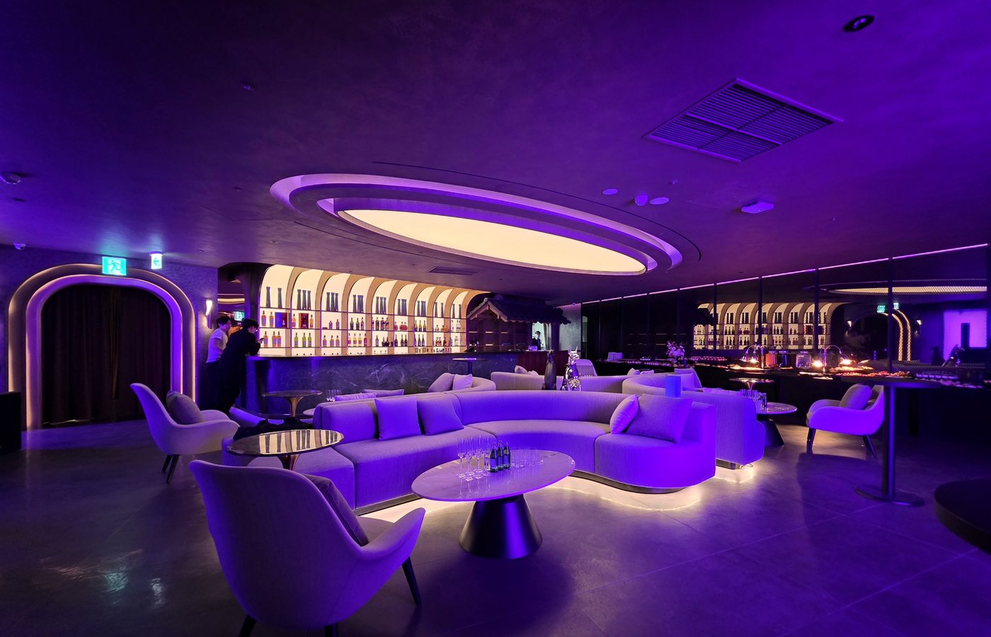 A refined lounge setting at Ultra Lounge, featuring sculptural seating, soft purple lighting, and an open bar backdrop designed for relaxed VIP hosting and late-night socializing.